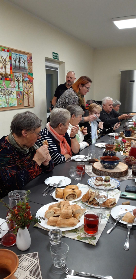 uczestnicy klubu seniora przy stole z potrawami gruzińskimi