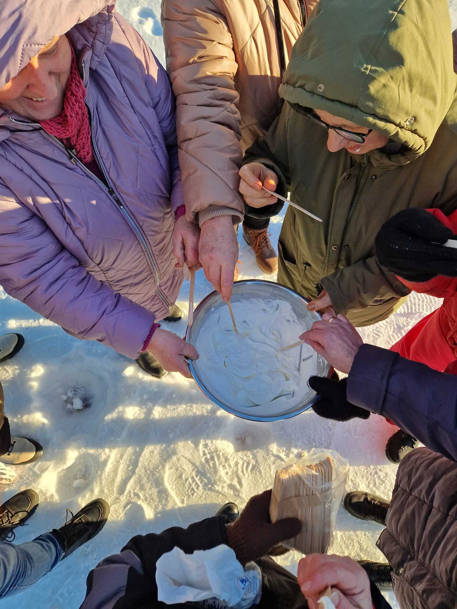 grupa osób uczestniczących w warsztatach tworząca deser na zewnątrz budynku