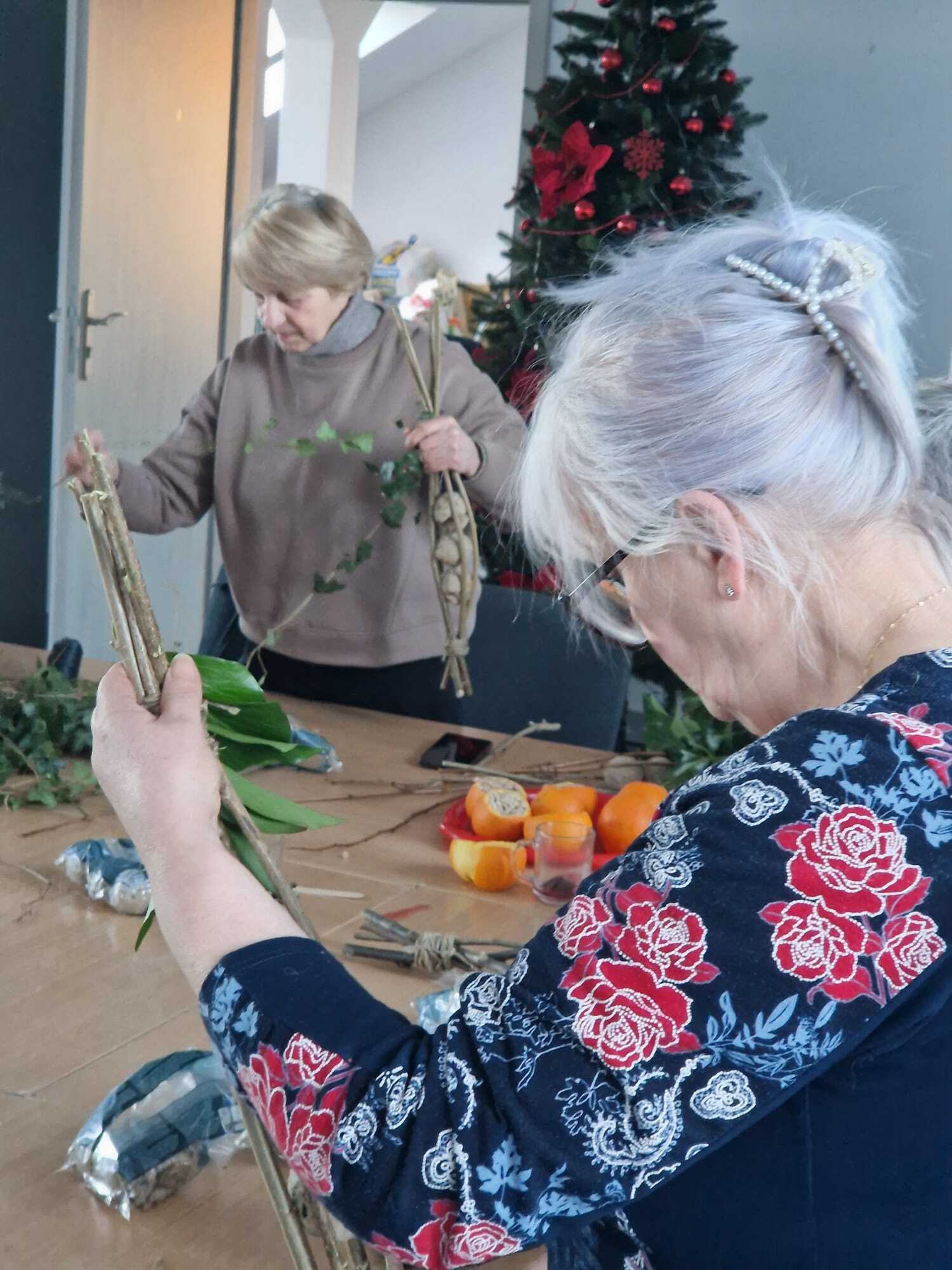 dwie uczestniczki warsztatów stojące przy stole tworzące karmniki dla ptaków