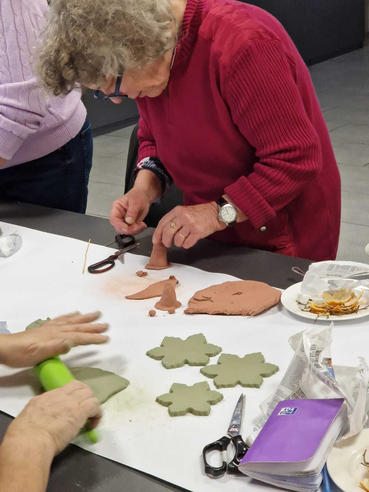 uczestniczka warsztatów przy wspólnym stole tworząca ozdoby ceramiczne