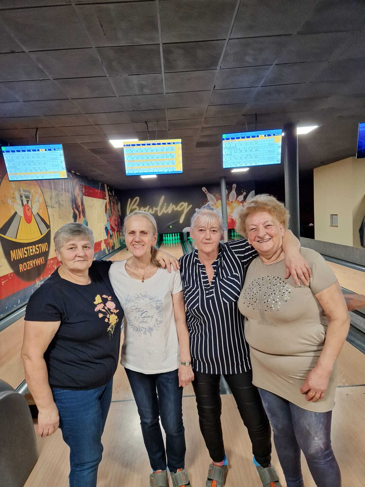 zdjęcie przedstawia stojące przy sobie cztery uczestniczki spotkania, w tle tory do gry w kręgle