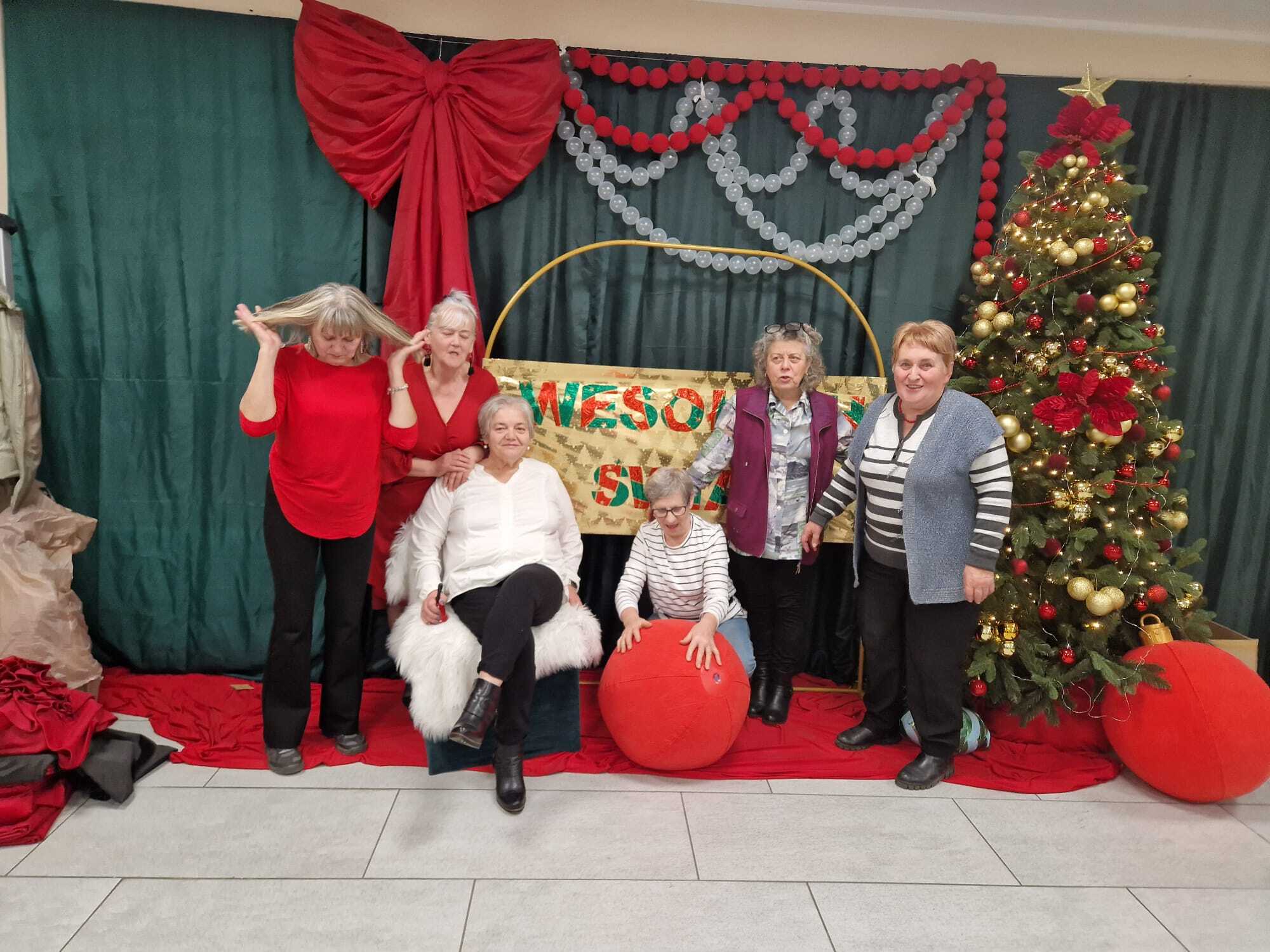 zdjęcie przedstawia uczestniczki klubu seniora stojące wspólnie przy choince bożonarodzeniowej