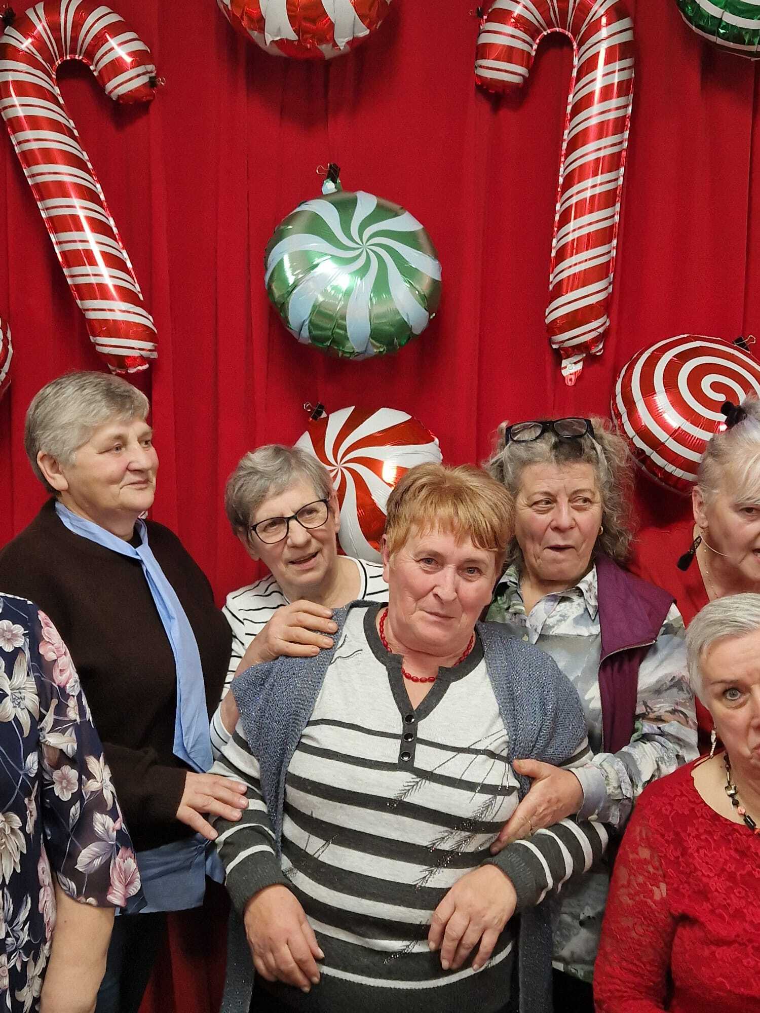 zdjęcie przedstawia stojące zadowolone uczestniczki spotkania, w tle na ścianie ozdoby mikołajkowe