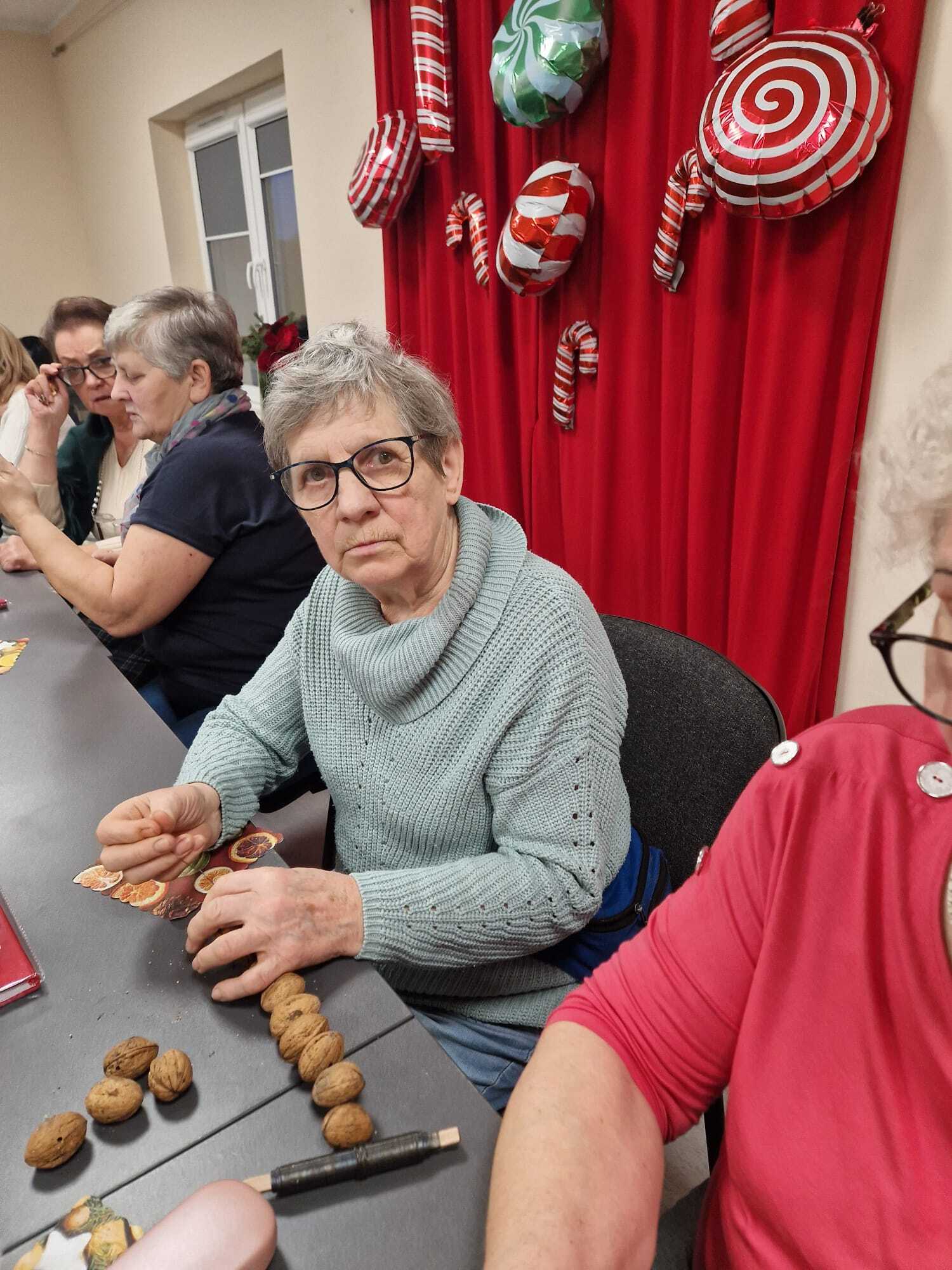 uczestniczki warsztatów psiedzące przy stole i tworzące ozdoby z orzechów