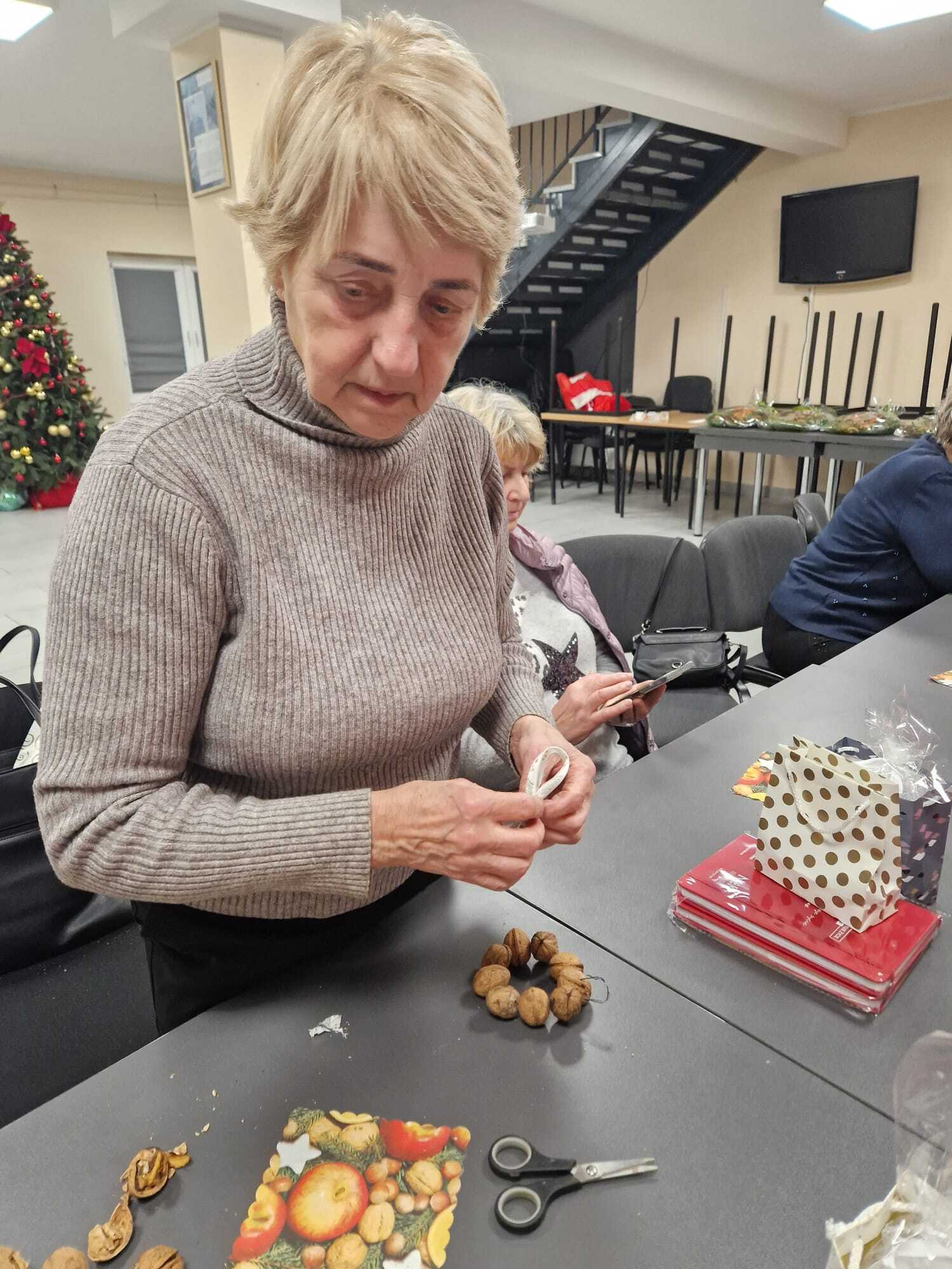 uczestniczka warsztatów tworząca orzechową ozdobę