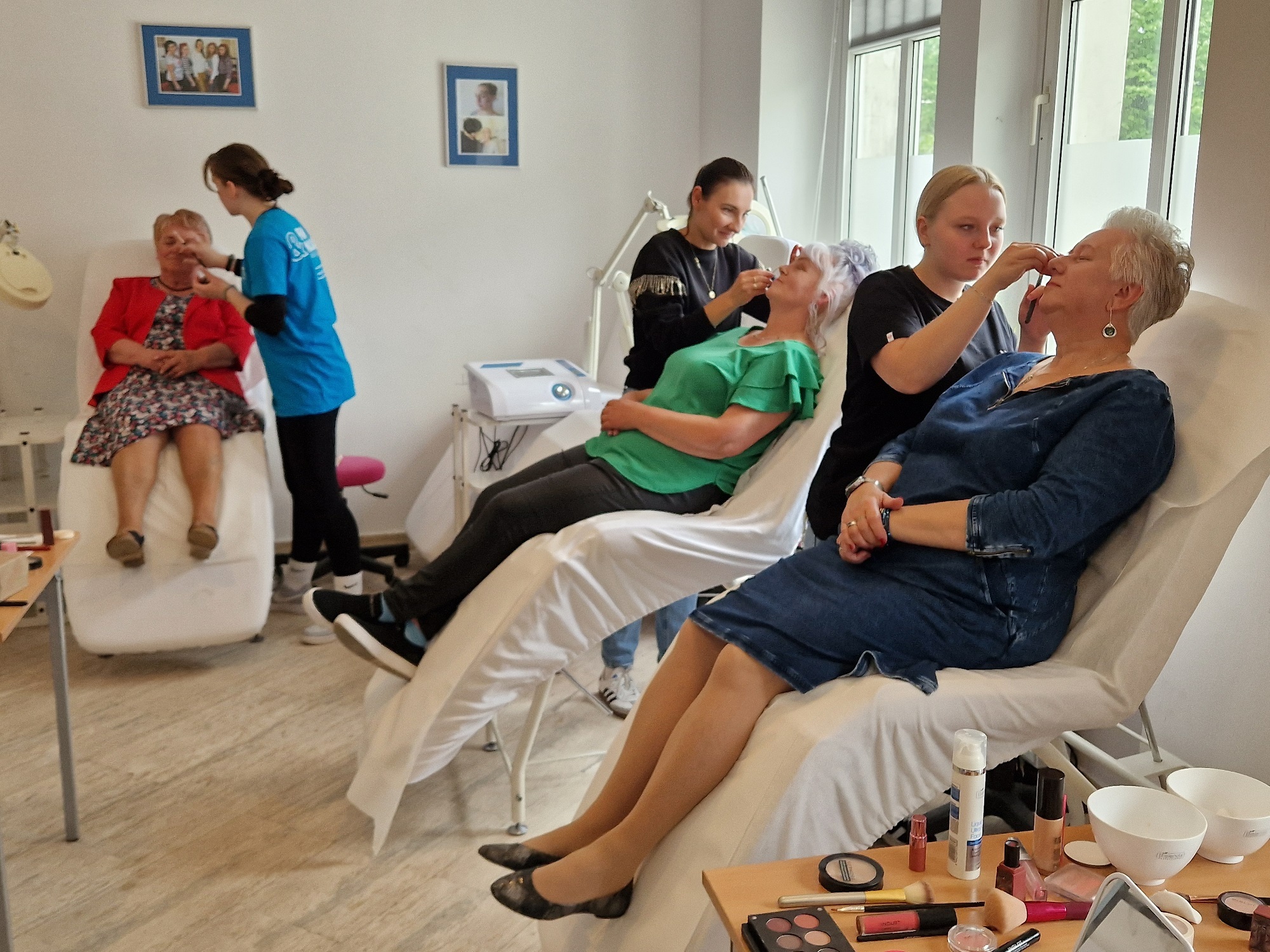 trzy uczestniczki sesji na fotelach podczas wykonywania makijażu przez uczennice