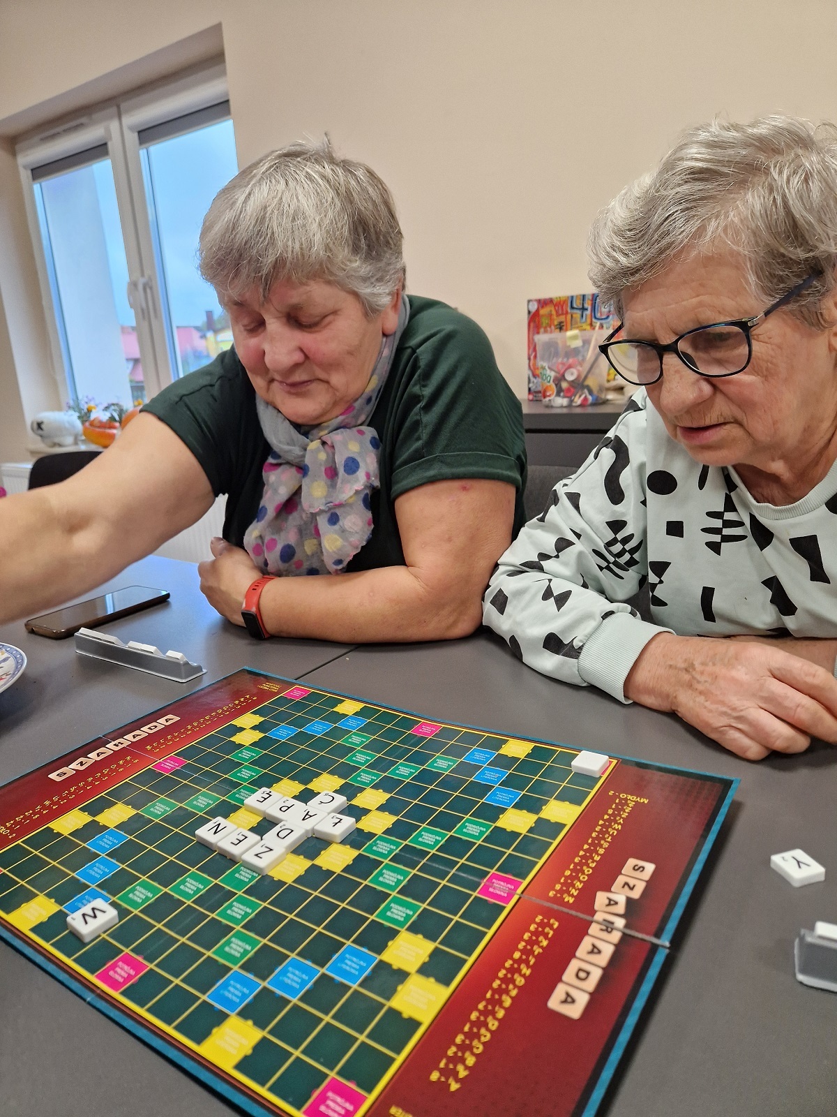 zdjęcie przedstawia dwie uczestniczki spotkania siedzące przy stole z grą planszową