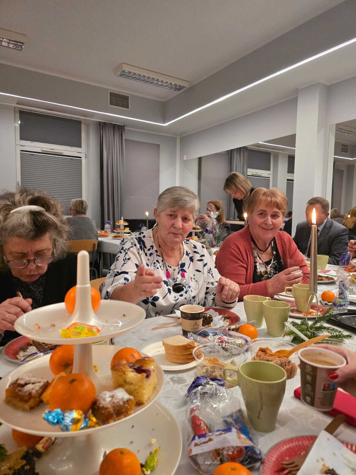 trzy uczestniczki spotkania siedzące przy stole wigilijnym spożywające przygotowane potrawy