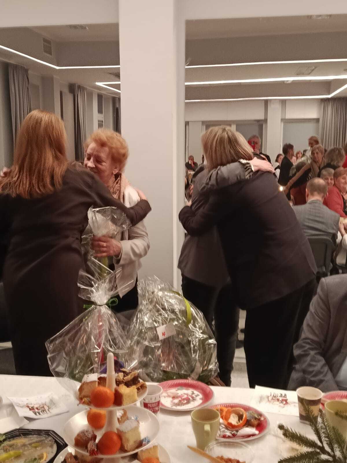 dwie uczestniczki Klubu Seniora przy stole wigilijnym składające życzenia dla Pani Burmistrz i Pani Skarbnik Kobylnicy